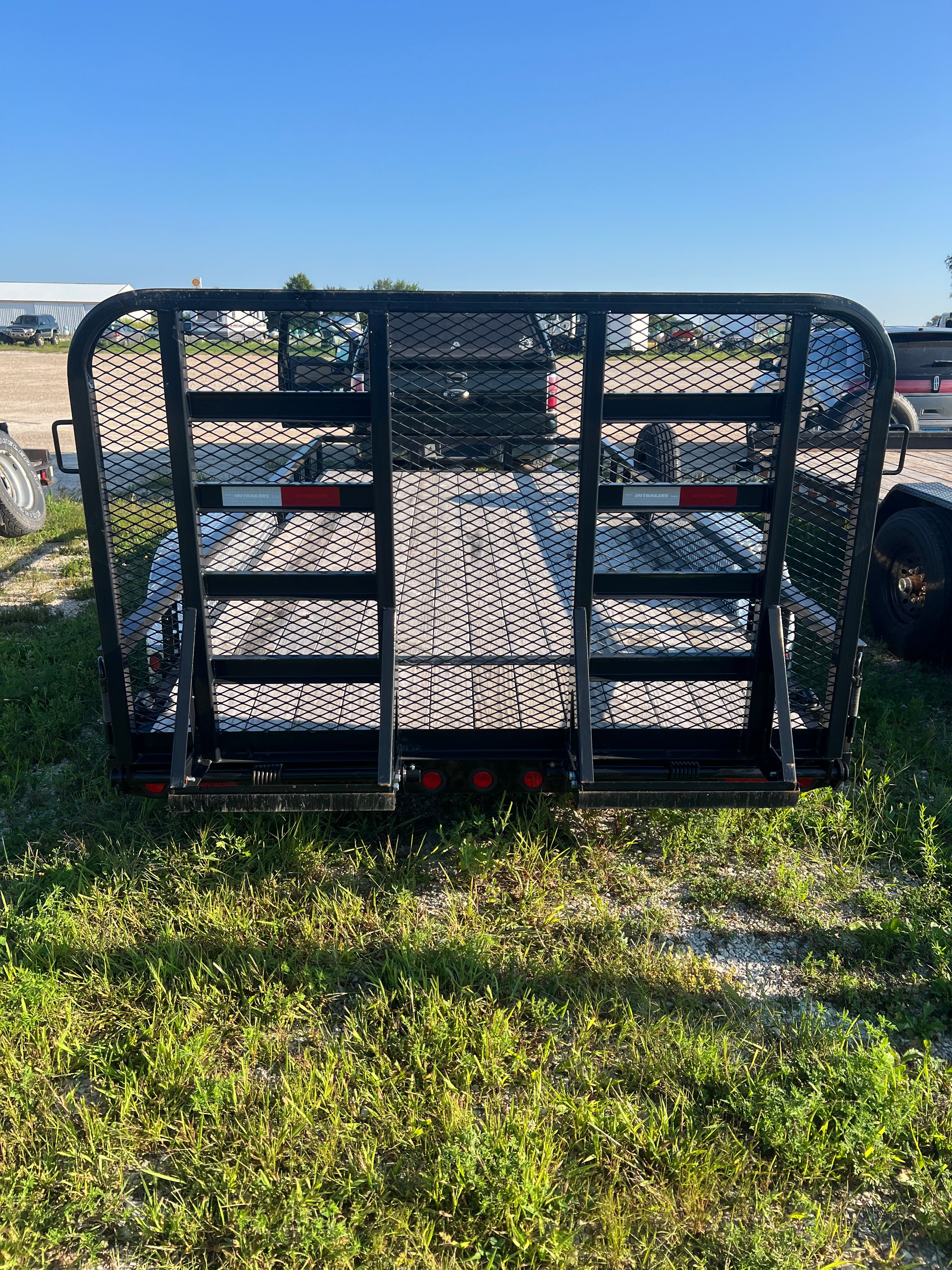 Utility trailer rear view with mesh gate raised showing wood deck