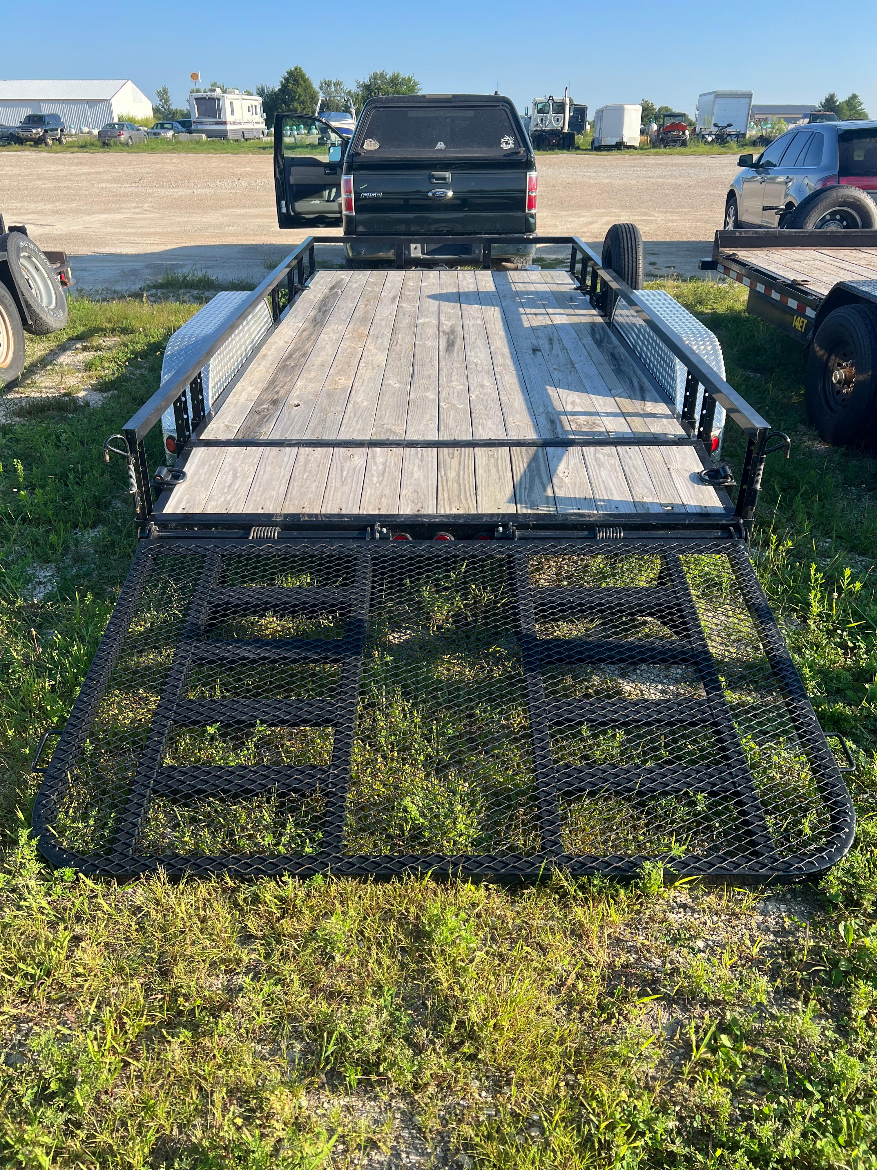 Utility trailer backed up to pickup truck with ramp gate down for loading